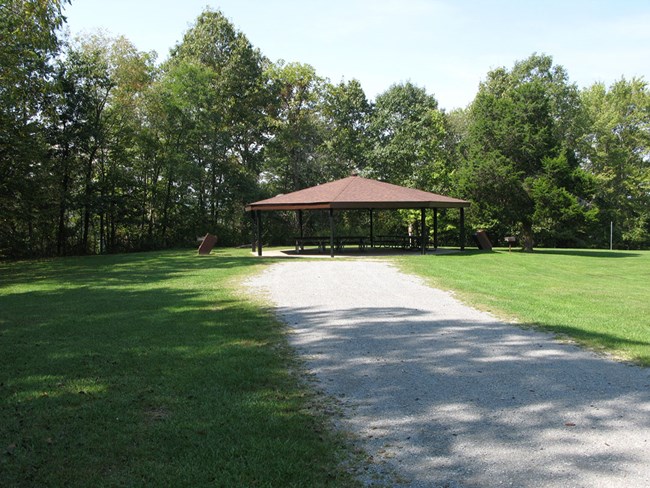 field with picnic shelter and woods behind