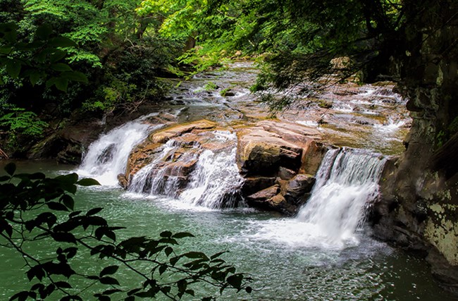 A wide creek flowing down over large rocks