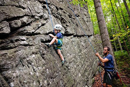 father belaying young boy on a rock cliff