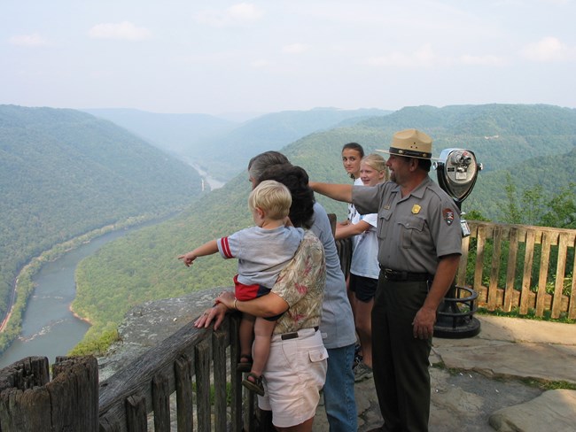 A ranger and visitors standing at a overlook of a deep gorge