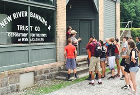 A group of visitors listen to a ranger in front of the New River Banking and Trust Co building.