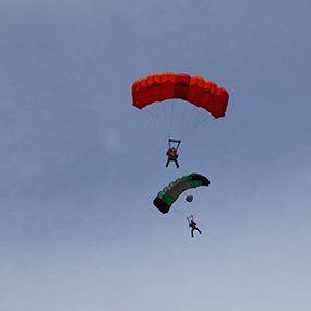 two base jumpers against a blue sky