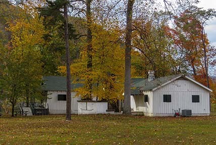 The white cabins of Camp Brookside surrounded by yellow, green and orange leafed trees