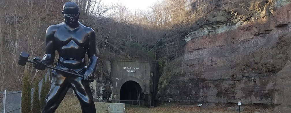John Henry statue in front of old railroad tunnel