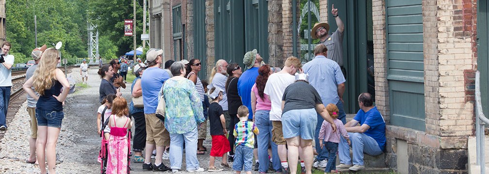 ranger with visitors by historic buildings