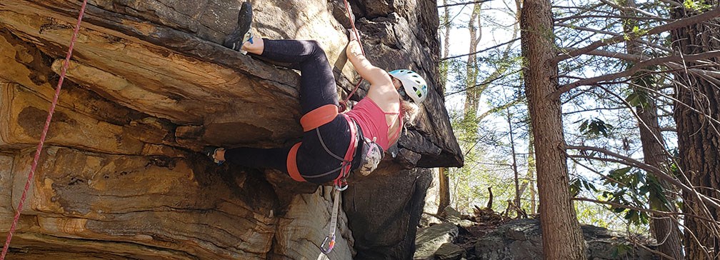 girl rock climbing on overhanging cliff