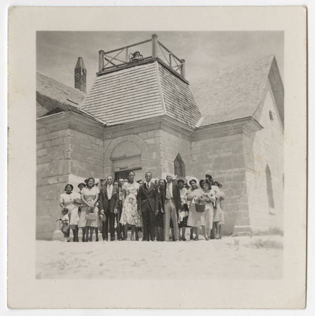 A group of people outside of a limestone church