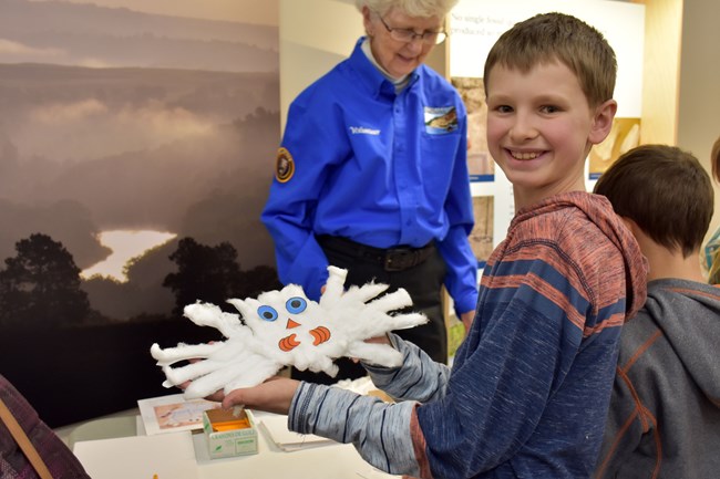 A young boy holds up a snowy owl craft