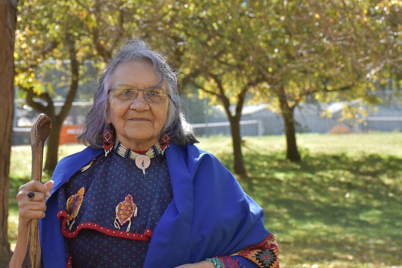 Native American Woman and Traditional Dress with walking stick in autumn