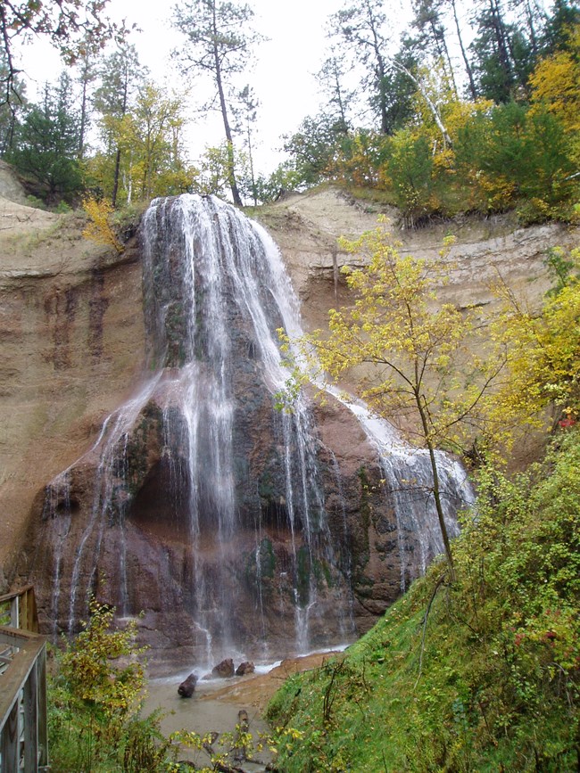 A waterfall flows off of the top of a rock outcropping and down into a basin