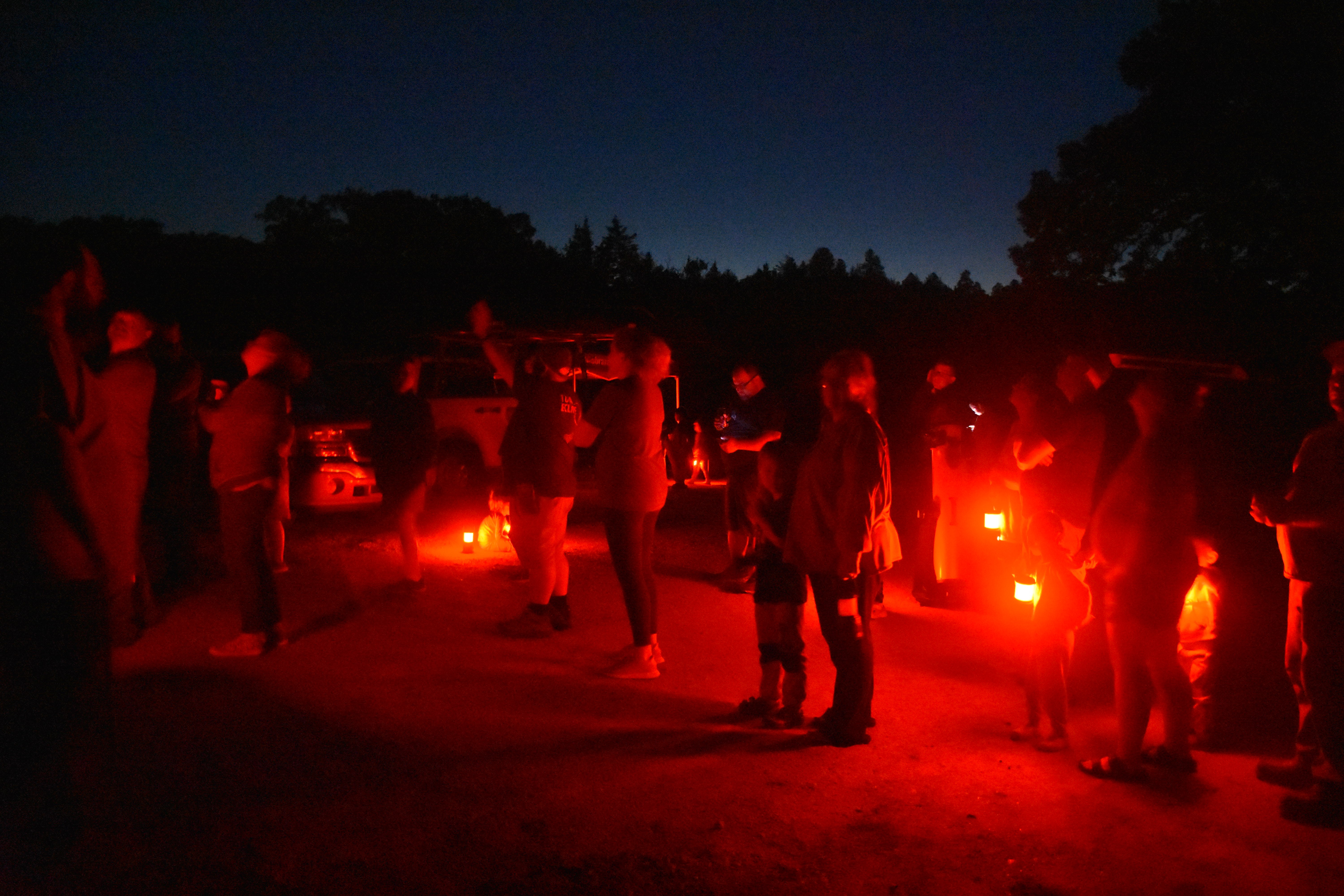 group of people looking up at the night sky standing in red light