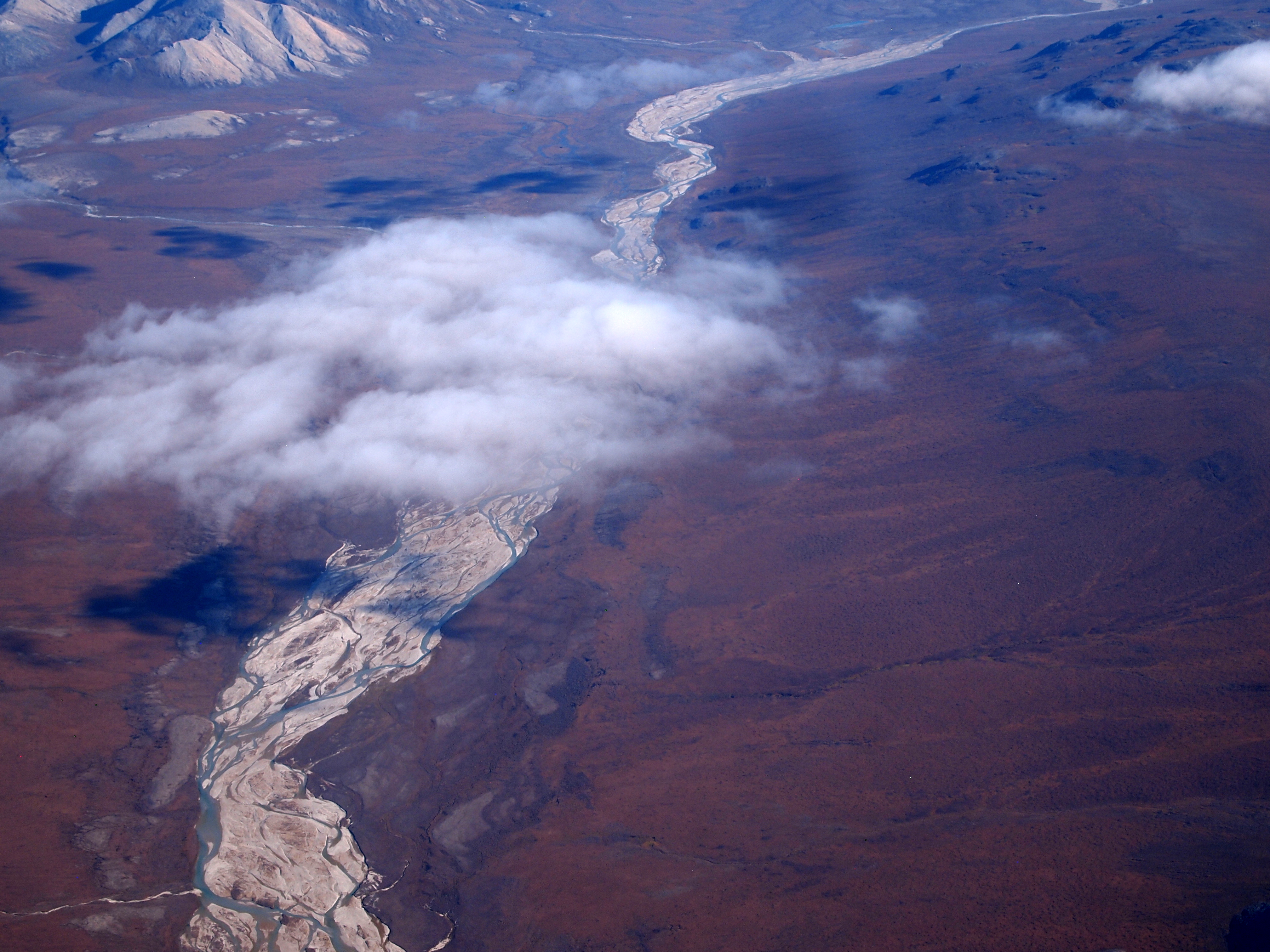 River running through tundra in fall colors of brown, orange, and gold.