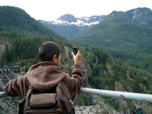 A student takes a photograph of a mountain.
