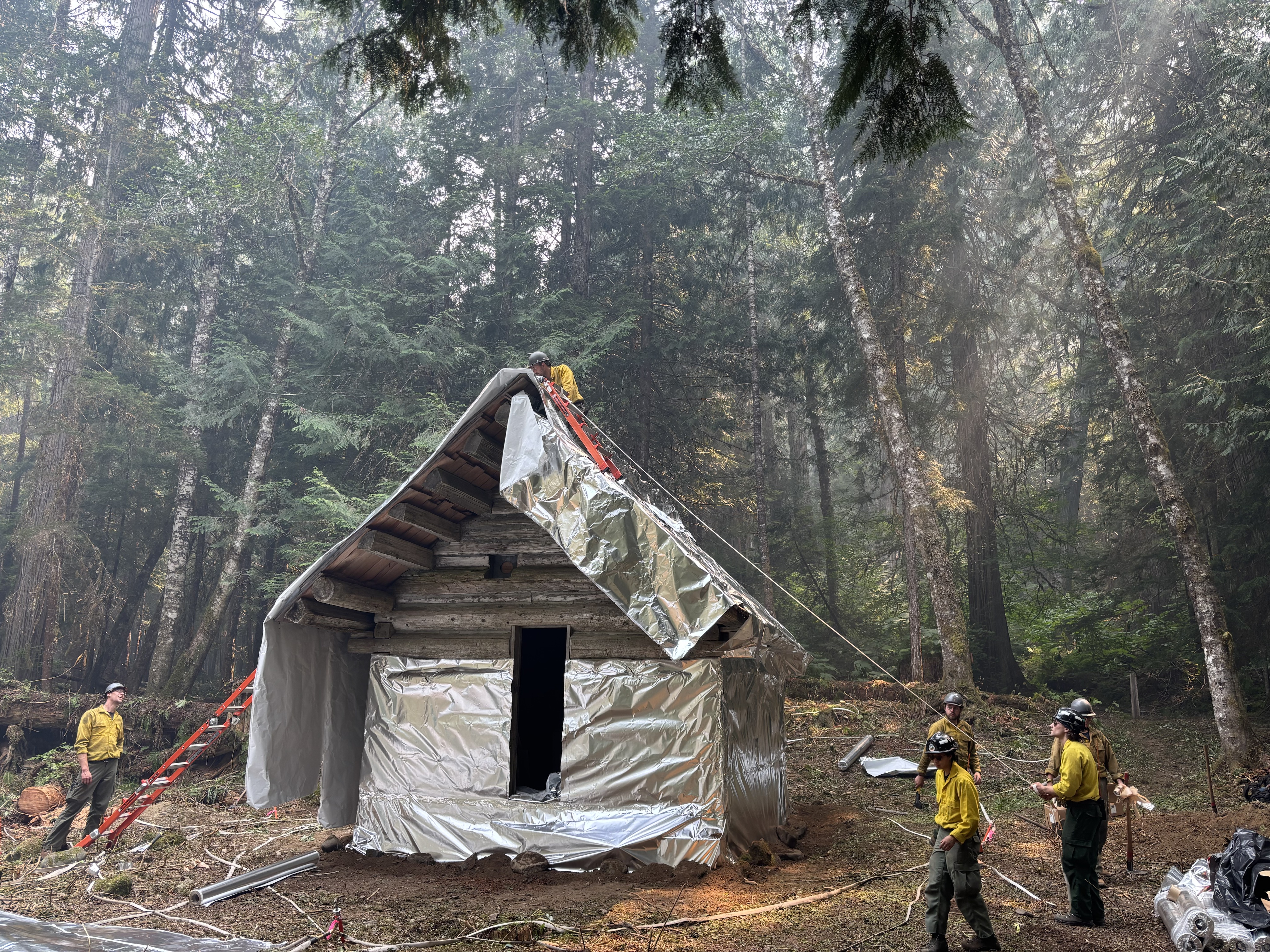 Firefighters putting fire protection on log cabin