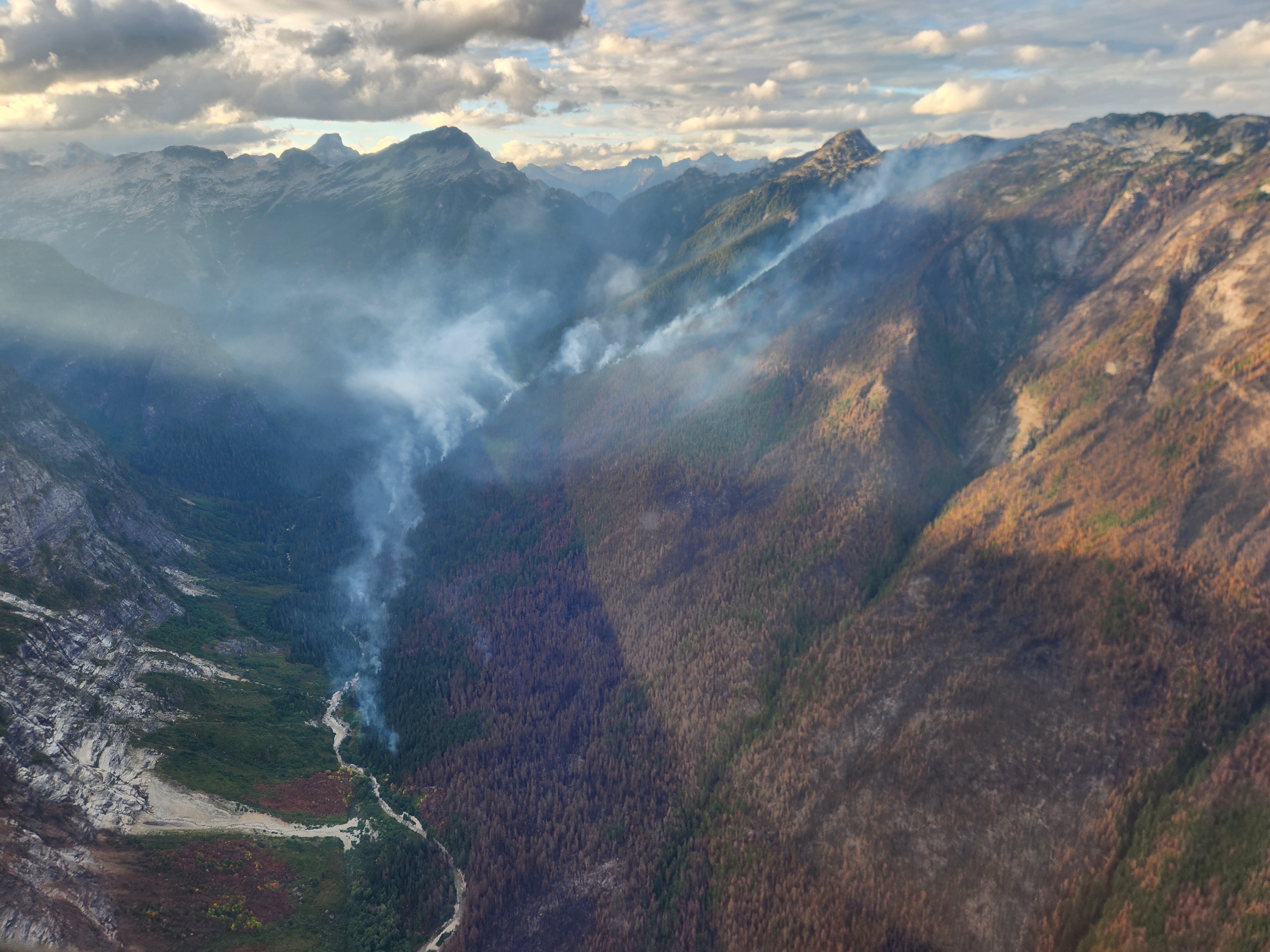NPS Photo Lexie Regetz Stettatle Drainage looking north Smoke wisps from a creek drainage in a forested mountain