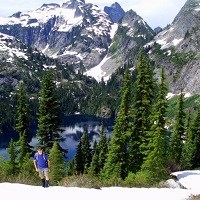 A hiker stands in front of a mountain lake