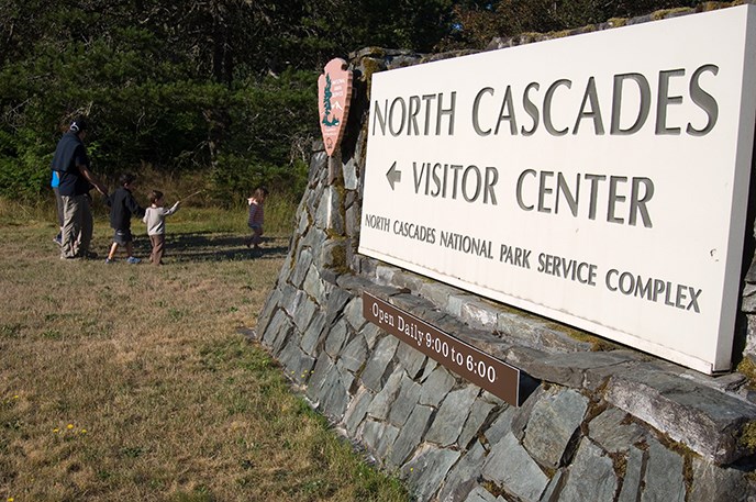 Morning bird hike participants walk past the North Cascades Visitor Center sign. Image Credit: NPS/NOCA/David Snyder