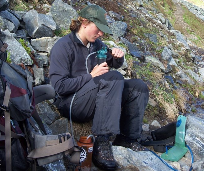 Hiker treating drinking water using portable filter