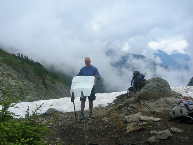 Hiker looking at map with clouds moving in
