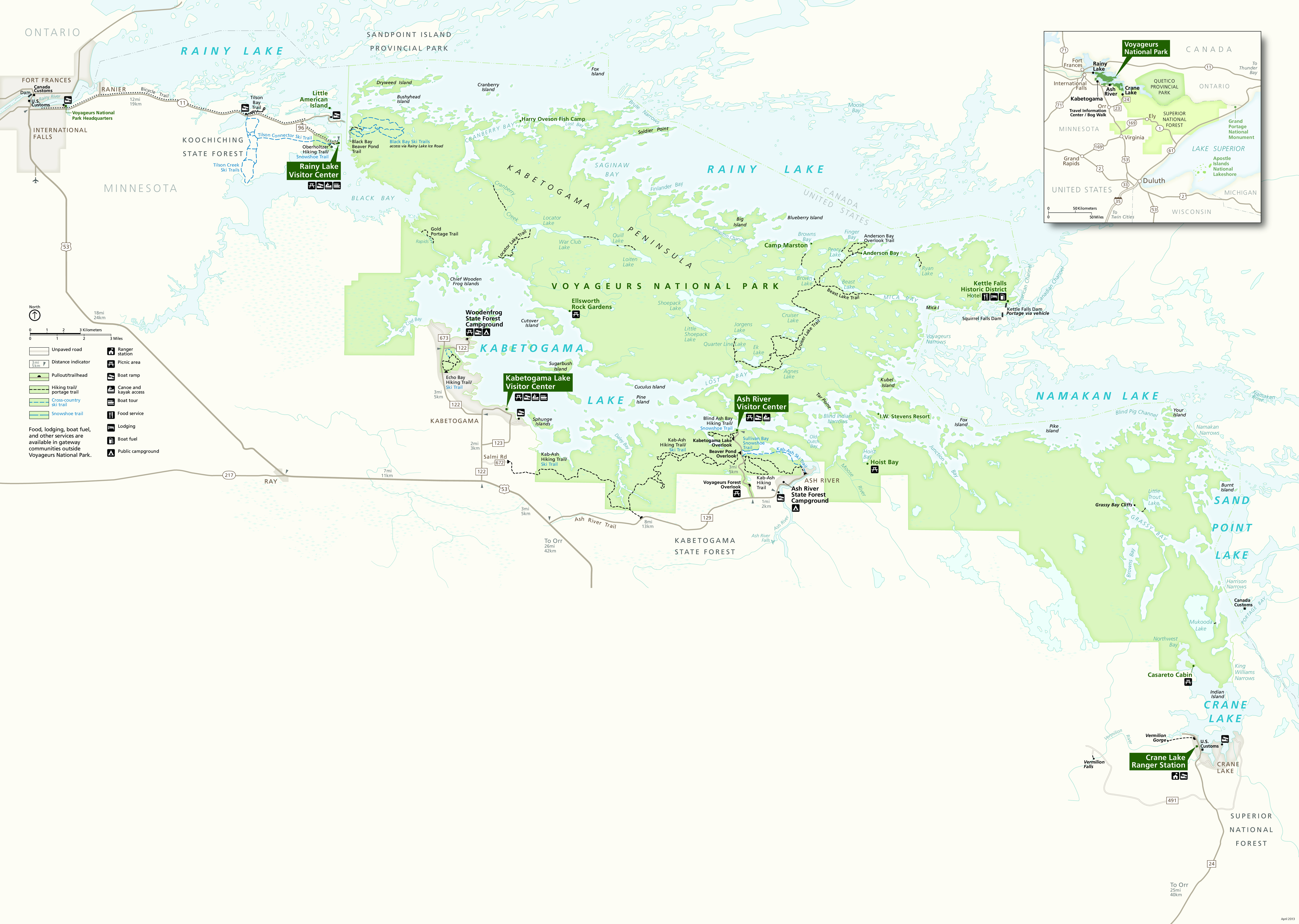 Park map of Voyageurs National Park in Minnesota. The park shown in light green, sprawls across the map from the top of the page to the bottom right and is surrounded by pale blue lakes and beige land area showing Minnesota, United States to the south of the park and Ontario, Canada to the north of the park. Four forest-green callout boxes identify Rainy Lake, Kabetogama Lake, and Ash River Visitor Centers along with Crane Lake Ranger Station.