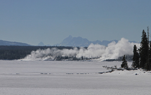 View across Yellowstone Lake to West Thumb Geyser Basin. Grand Teton Mountain Range 50 miles in the distance