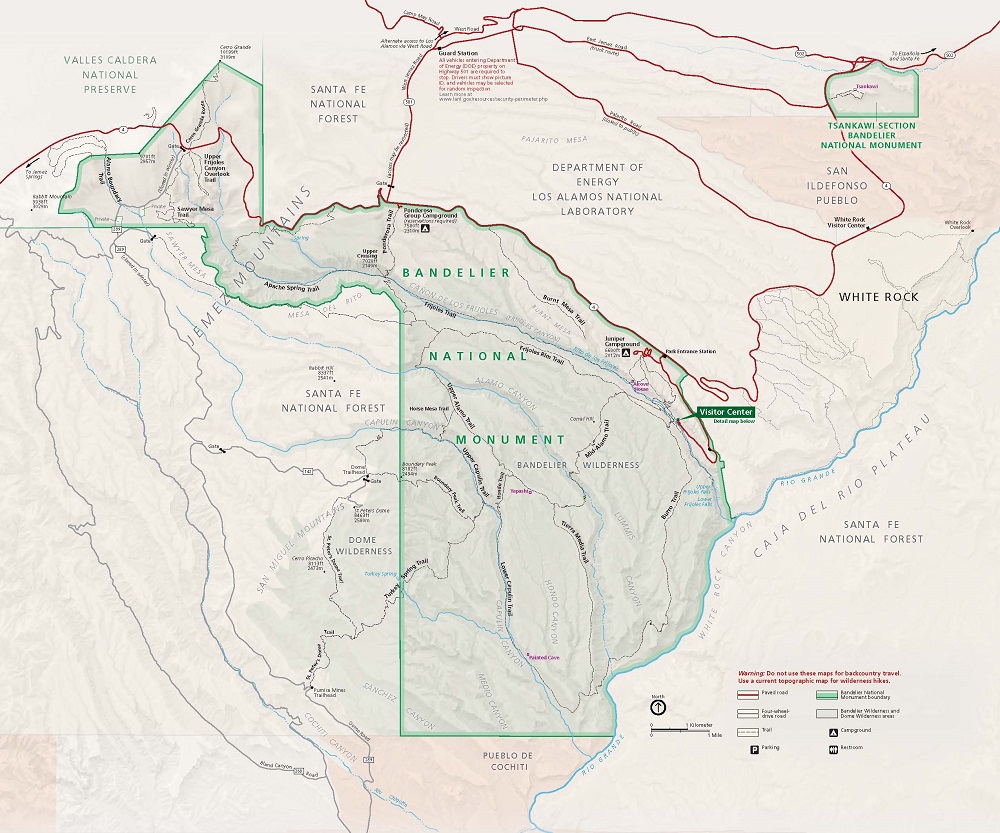 Map of Bandelier National Monument in New Mexico. The park is shown in green, surrounding areas in beige, trails in black dashed lines, and roads as red lines.