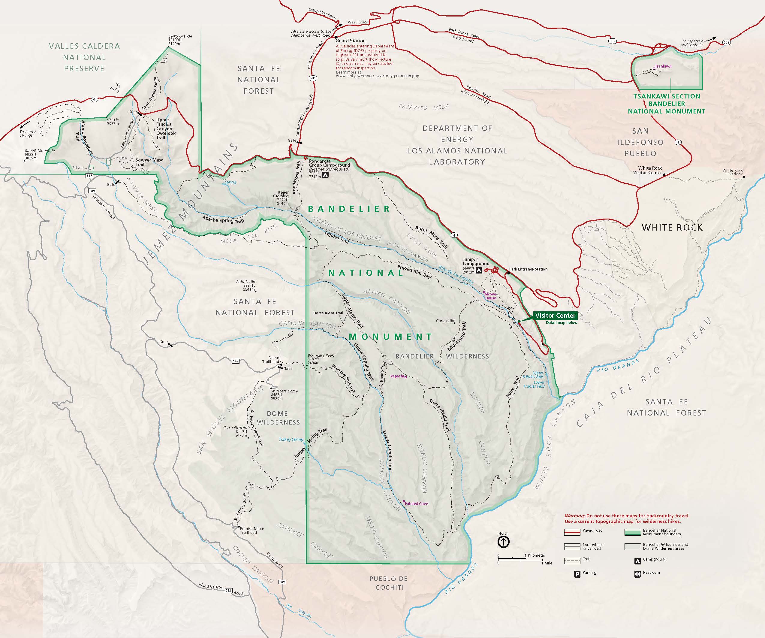 Map of Bandelier National Monument in New Mexico. The park is shown in green, surrounding areas in beige, trails in black dashed lines, and roads as red lines.
