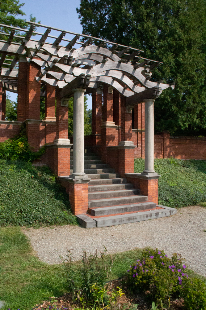 A brick and timber pergola with trellis roof.