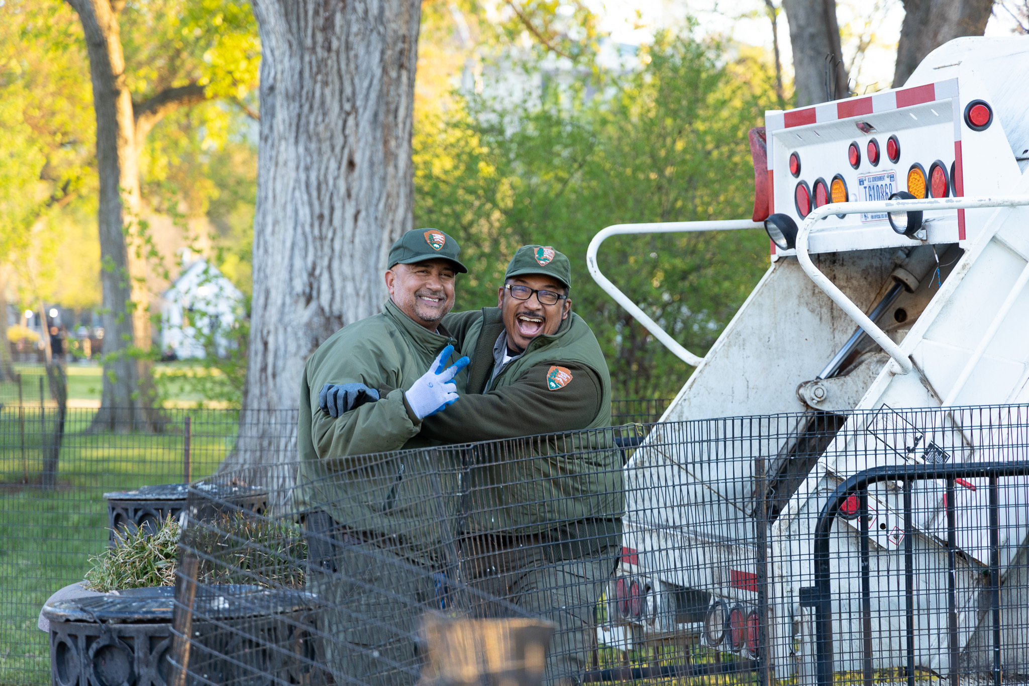 Two park rangers smile and hug while holding up a peace sign.