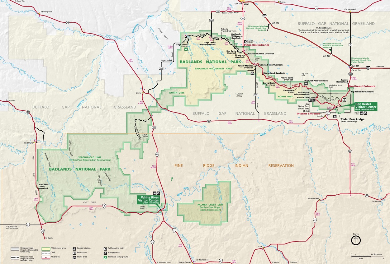 Map of Badlands National Park in South Dakota. The park is highlighted in green with surrounding terrain shown in light yellow, tan, pearl white, or pale peach. Red lines represent roads and yellow dots represent towns and cities.