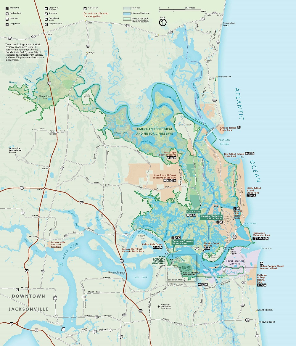 Map of Timucuan Ecological and Historic Preserve in Florida. The park, an irregular hook shape, is lime green with acid wash-like speckling within a swirl of peach, lavender, and cyan, surrounding lands pale sage with burgundy highways. The sky-blue Atlantic Ocean runs along the right edge of the map.