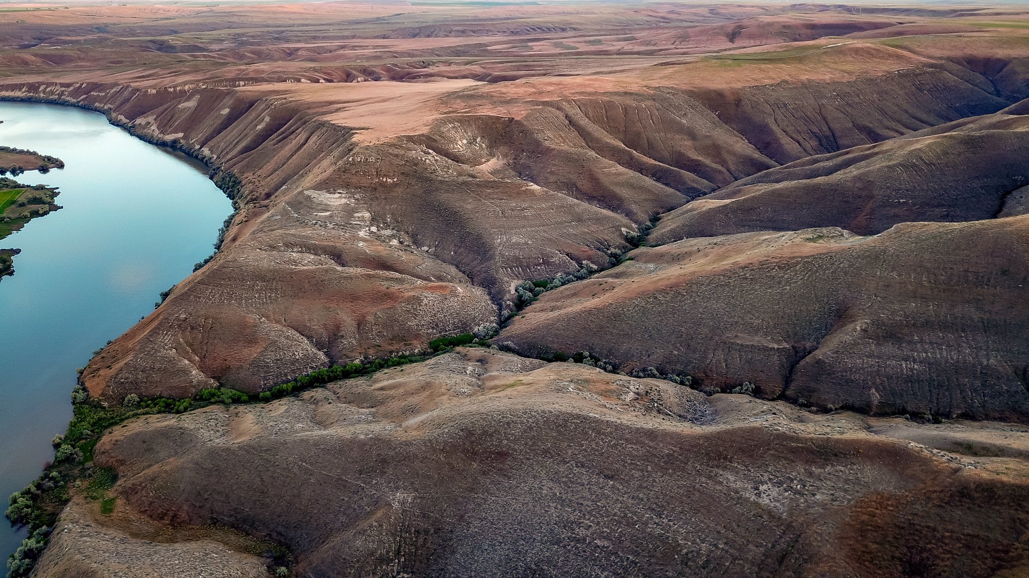 view of the fossil beds from a drone up high showing the folds of land and part of the Snake River