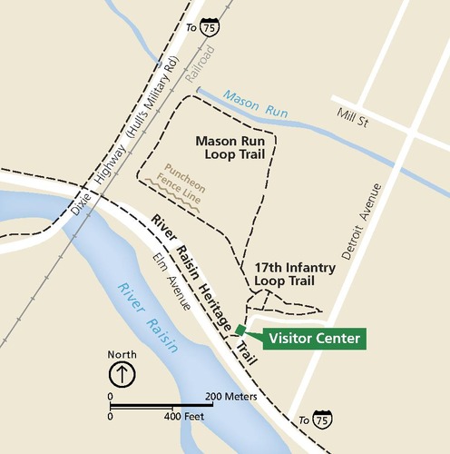 Map of River Raisin National Battlefield Park in Michigan. Lands are shaded pale yellow, hashed with black dashed trails, white roads, and two sky blue rivers. Near the bottom of the map, a small kelly green square with a callout box reads “Visitor Center.”