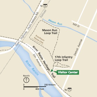 Map of River Raisin National Battlefield Park in Michigan. Lands are shaded pale yellow, hashed with black dashed trails, white roads, and two sky blue rivers. Near the bottom of the map, a small kelly green square with a callout box reads “Visitor Center.”