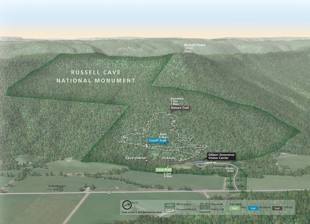 3D park map of Russell Cave National Monument in Alabama. A diagonally oriented bowtie-shaped area outlined in green represents the boundaries of the site with trails and other landmarks marked throughout the lower half of the forested landscape.