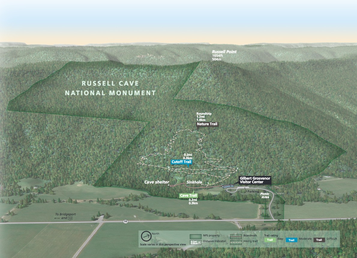 3D park map of Russell Cave National Monument in Alabama. A diagonally oriented bowtie-shaped area outlined in green represents the boundaries of the site with trails and other landmarks marked throughout the lower half of the forested landscape.
