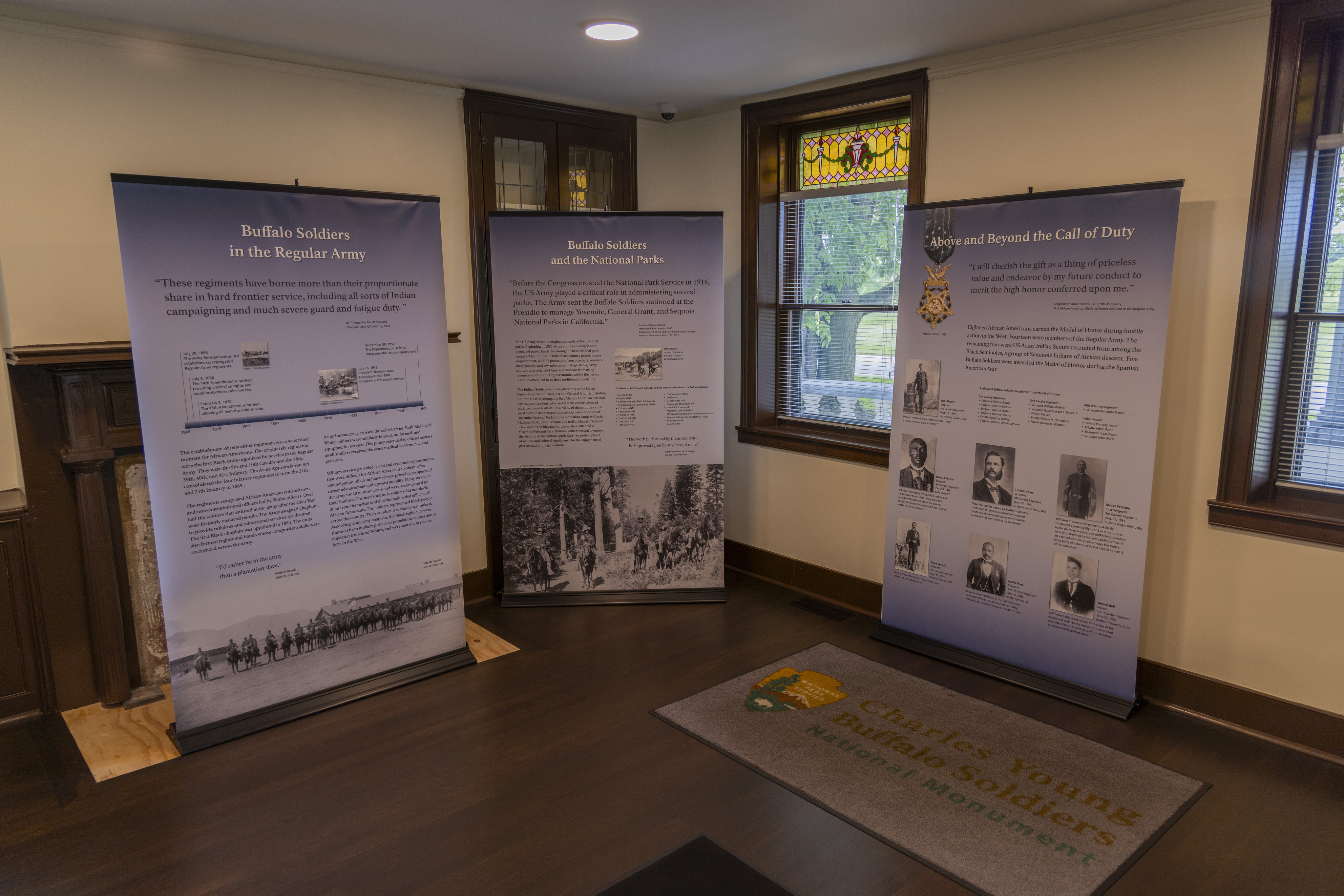 Three light blue-colored pull-up banners with text and photos on them inside of a room in the Young family home.