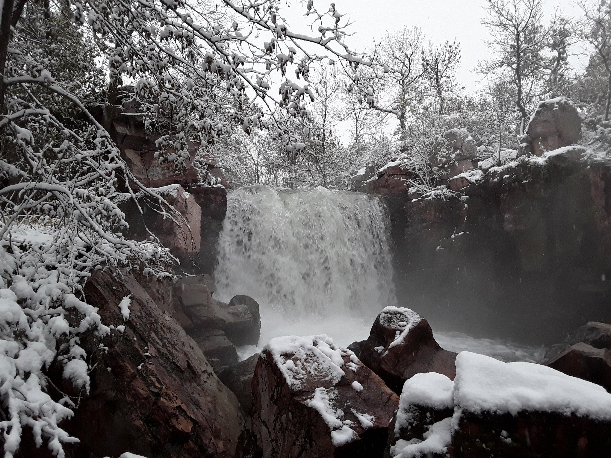 Waterfall pouring over snow-covered scenery in winter