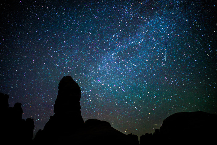 a starry sky above silhouetted rock pinnacles