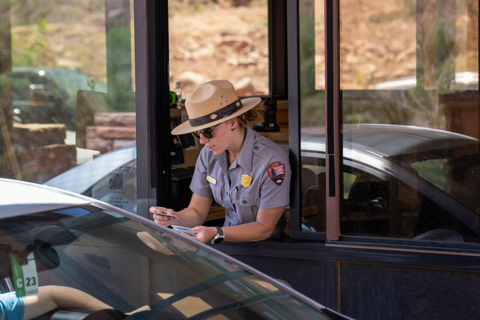 A fee ranger in a fee booth gives a visitor information as they enter the park in their car.