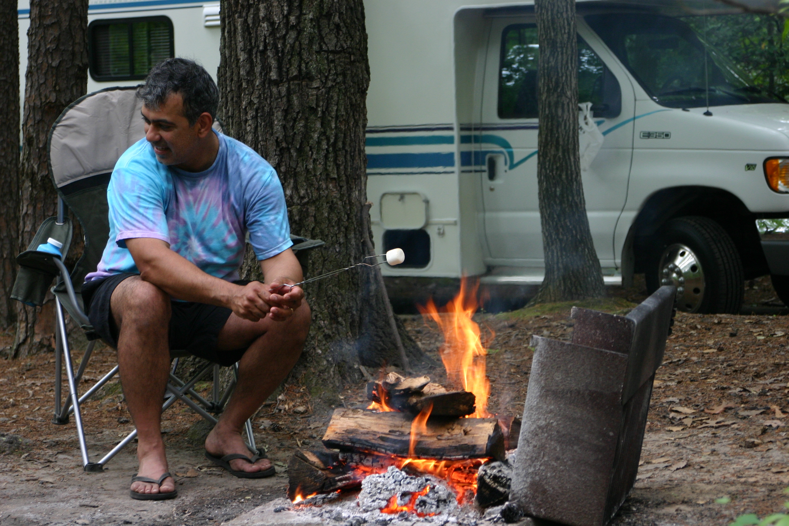 Youth retreat camper roasting a marshmallow at a designated campground fire ring
