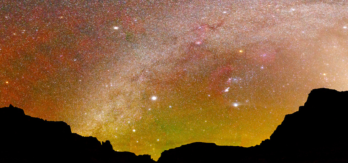 Yellow, red, and orange night sky exposure over silhouetted canyon walls
