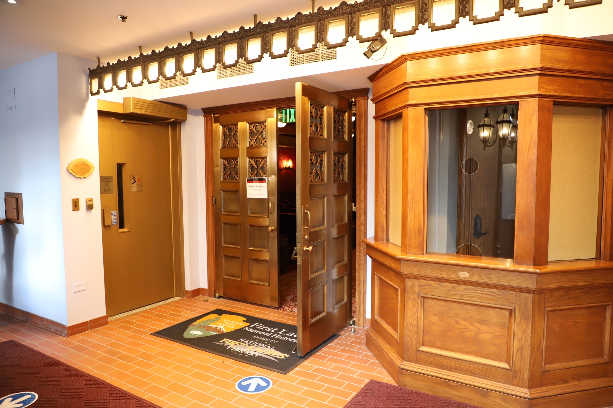 Brass doors opening to revel a peak of an historic theater. 
