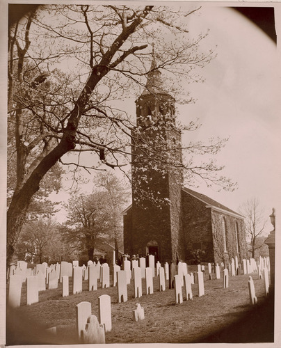 Church and steeple, showing people, and adjoining cemetery, with many gravestones 