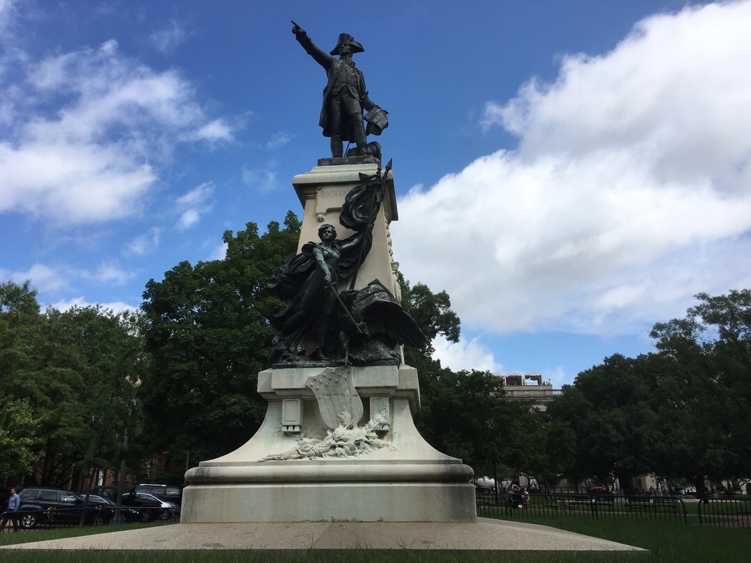 A statue of General Rochambeau on top of a pedestal. He is pointing into the distance. Another bronze statue is below him.