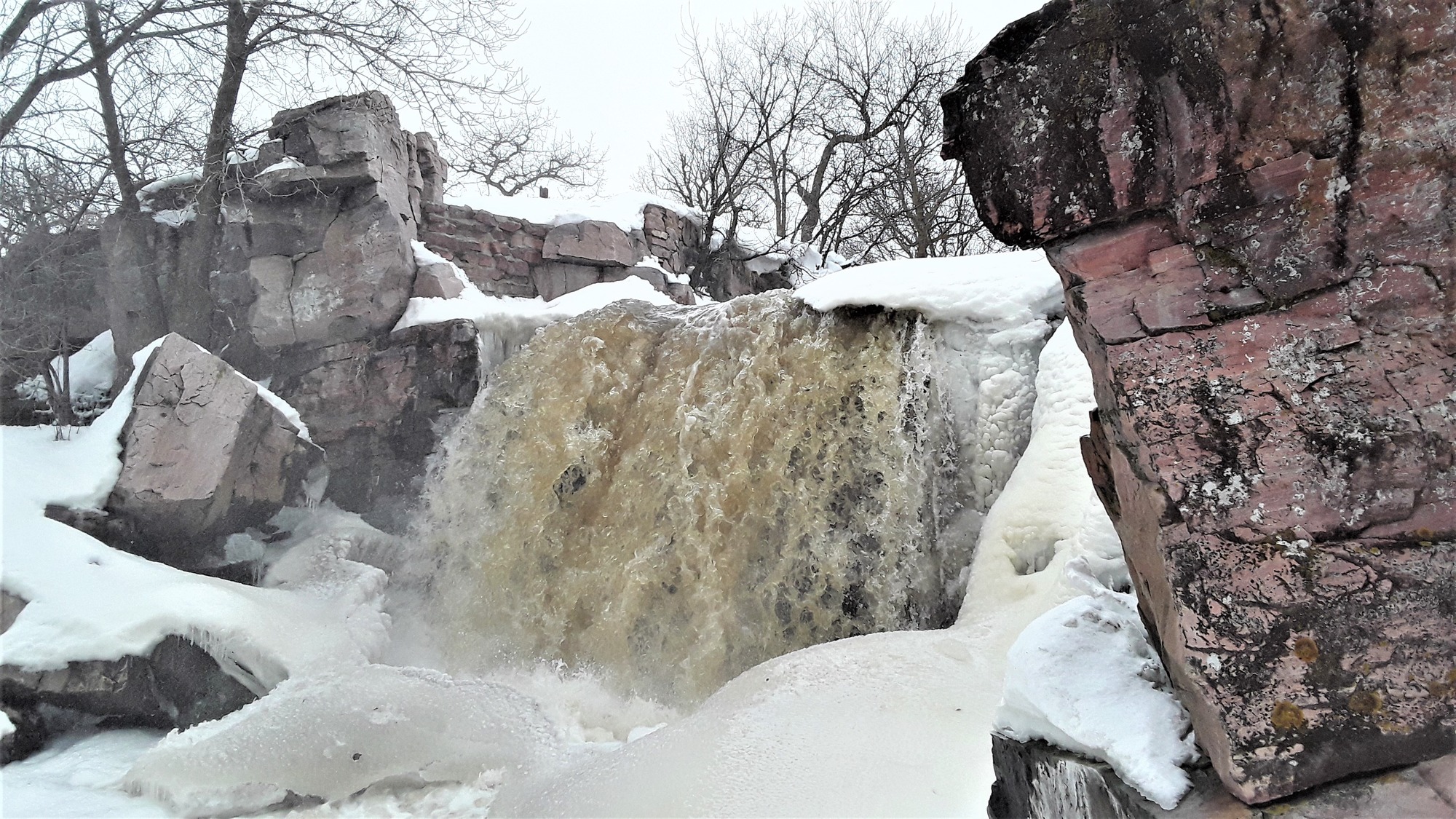 Roaring waterfall surrounded by ice and rocks