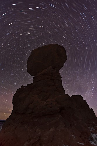 stars wheel around a silhouetted rock formation