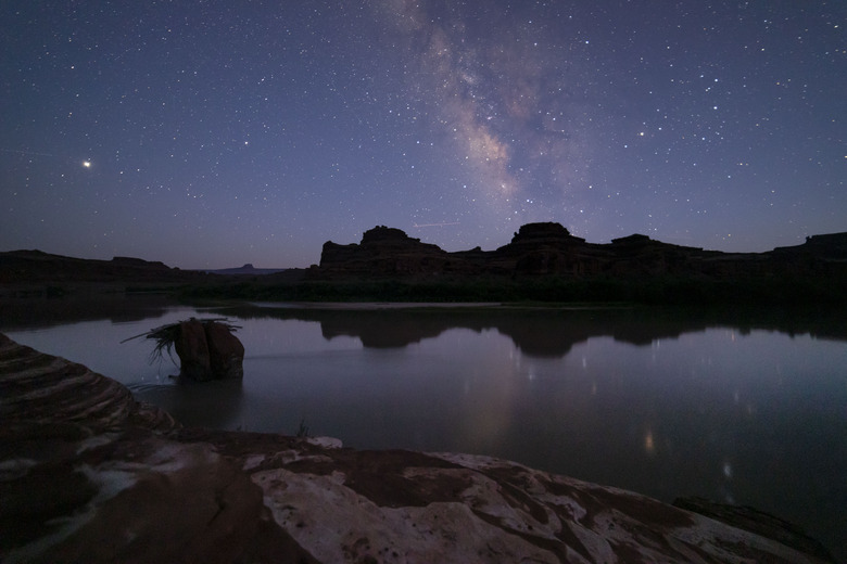 Blue and purple night sky with stars reflected in a river