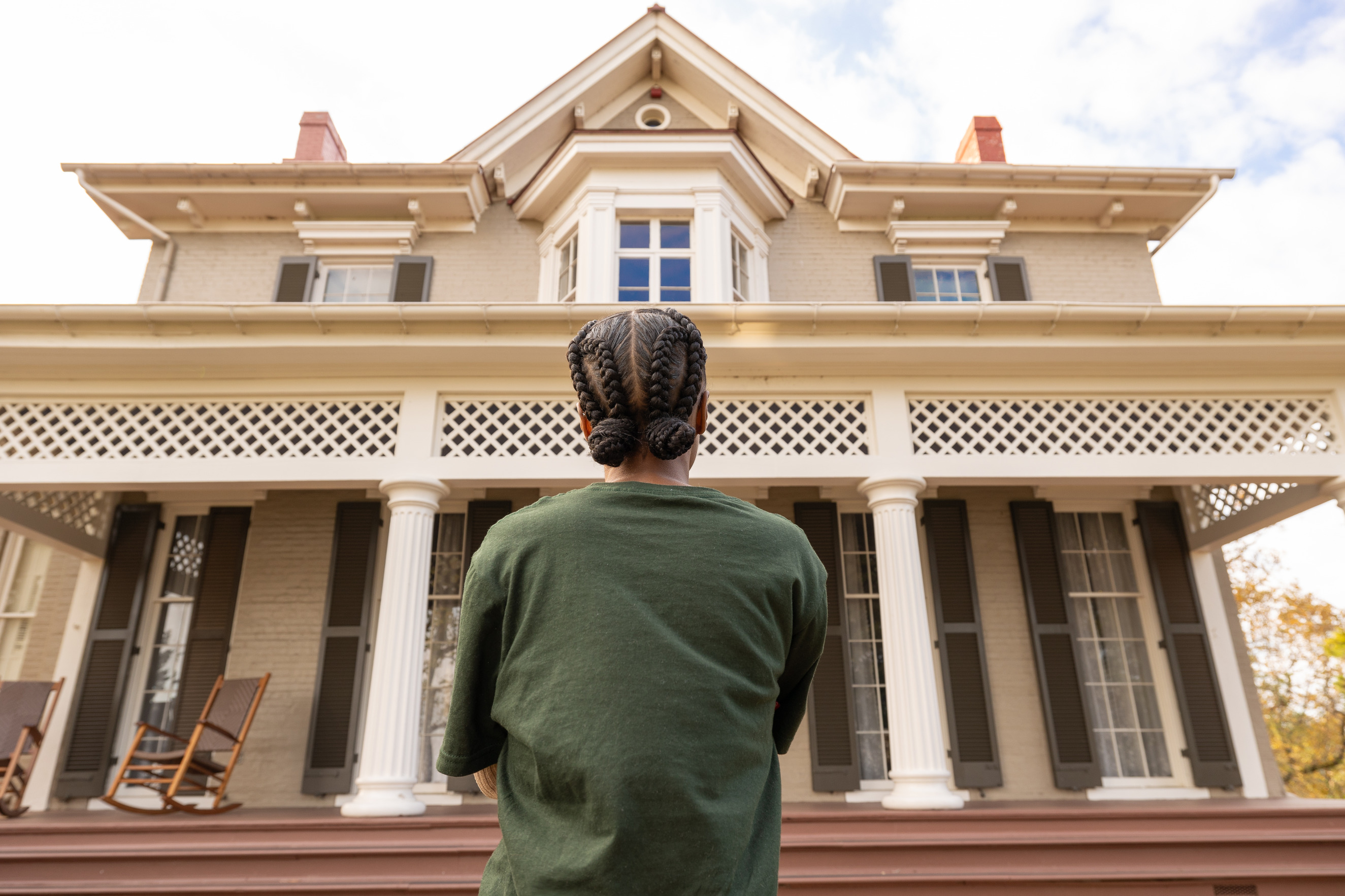 A National Park Service Youth Intern stands in front of the Frederick Douglass National Historic Site home. 
