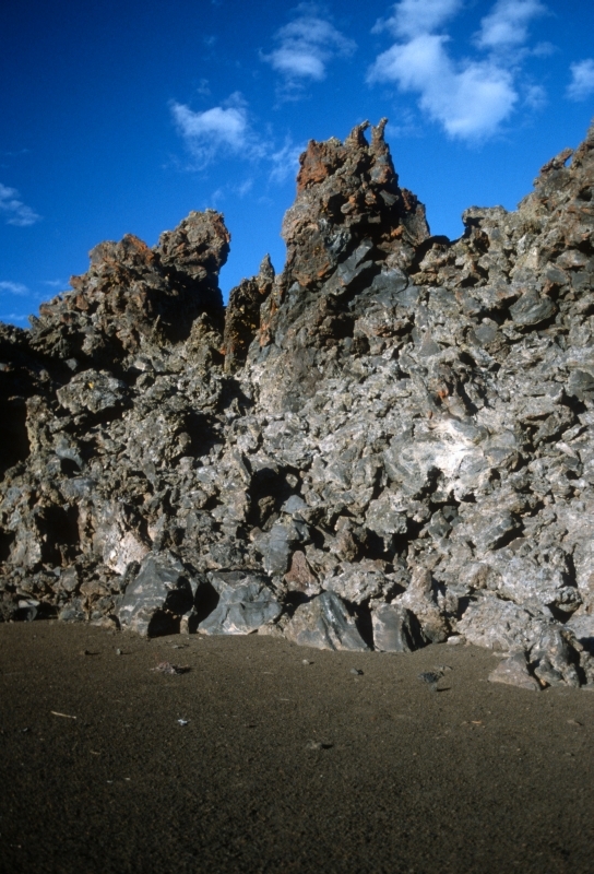 a tall pile of dark chunky rocks on a flat dark cinder ground
